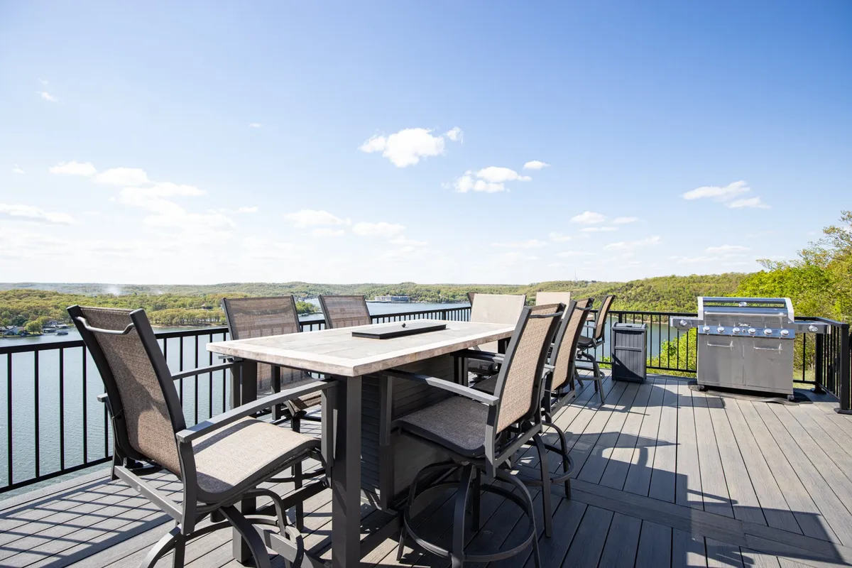 A cheerful exterior setup with an outdoor dining table and grill set against the backdrop of the lake. The scene invites guests to enjoy barbecues, meals, and morning coffee while overlooking the water.