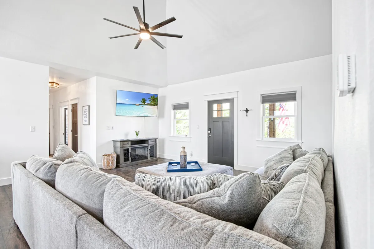 A spacious living area with a large sectional sofa, coffee table with décor, flat-screen TV, and a clear view of the front door. The arrangement is inviting and functional, ideal for relaxation and gathering.