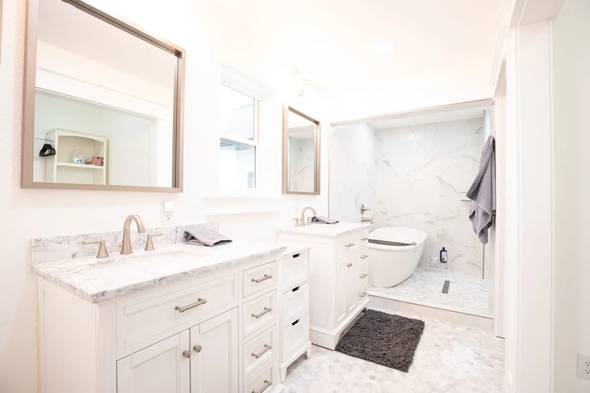 A luxurious bathroom with a marble double vanity, large mirrors, and a striking freestanding bathtub. The elegant finishes and open space evoke a spa-like feel, inviting guests to indulge in relaxation and self-care.