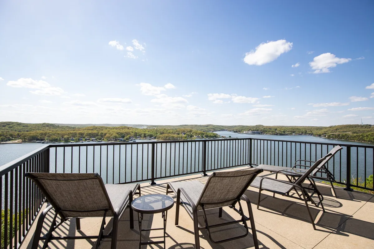 A tranquil exterior scene featuring lounge chairs and an outdoor table positioned to enjoy sweeping views of the lake. The mood is peaceful yet social, inviting guests to relax, socialize, or watch the sunset together.