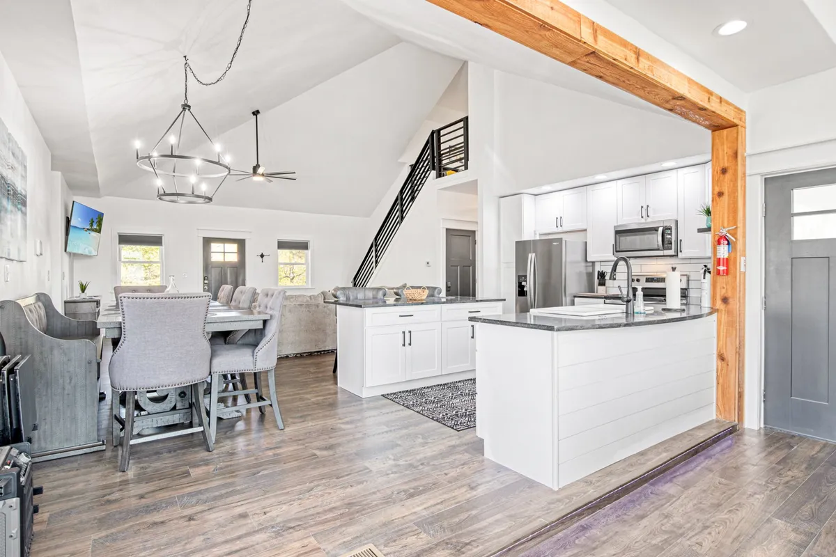 A wide-angle shot capturing the unified living room, dining area with a large table, and kitchen island. The scene is lively and welcoming, showing how all spaces are interconnected, with ample room to host guests or family members for any occasion.